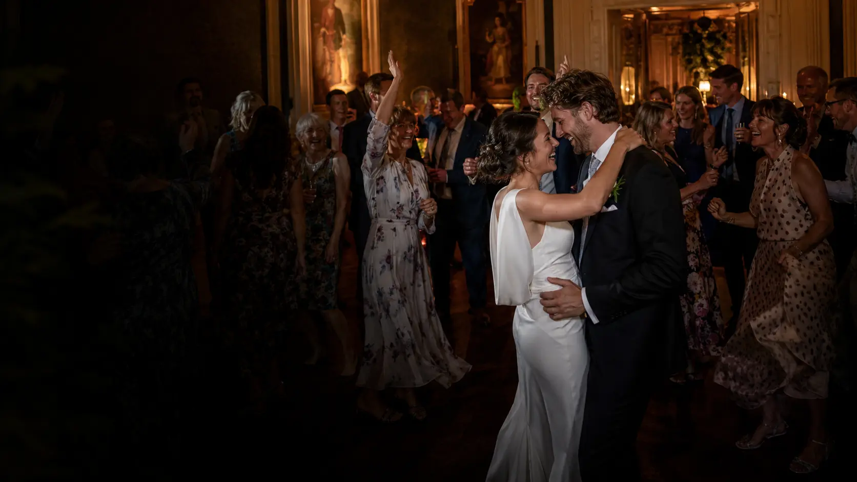 A newly married couple dancing together among smiling friends and family